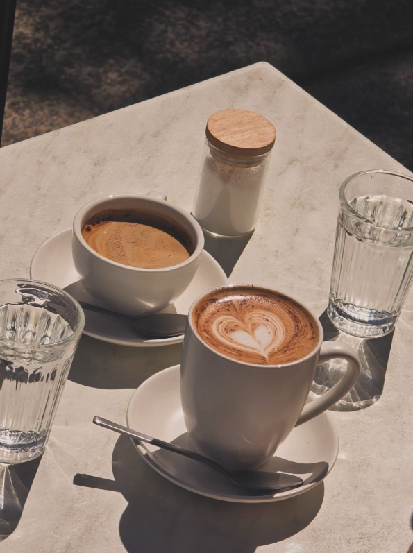 Two coffees on a sunlit outdoor table